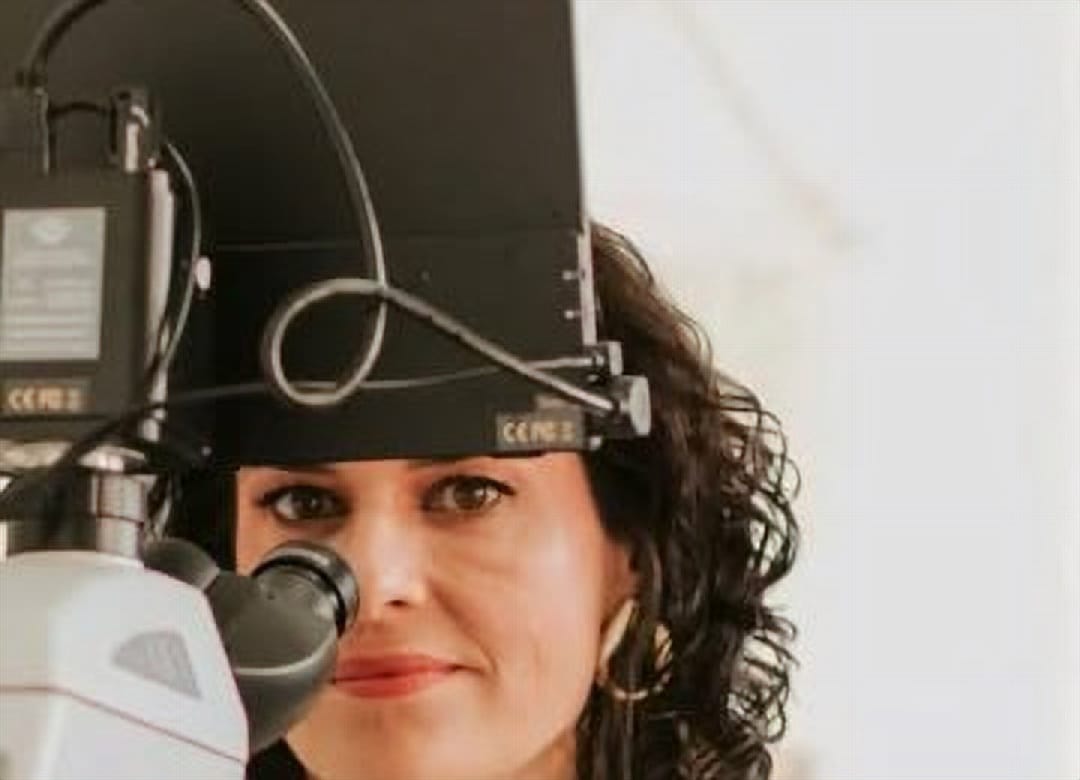 Dra. Fernanda ao microscópio, no consultório da Clínica DUO